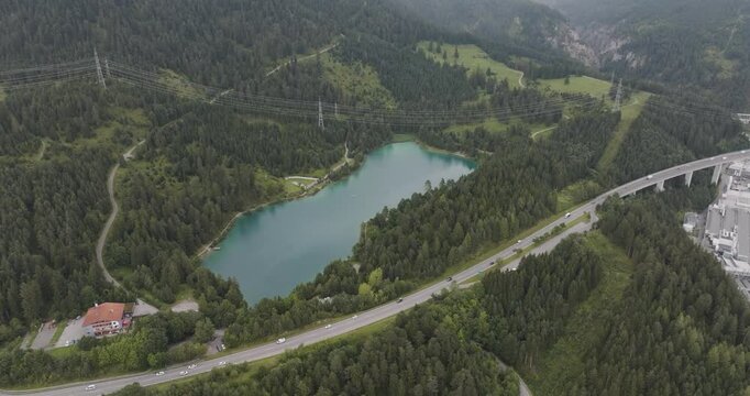 Aerial view of tranquil lake surrounded by picturesque mountains and lush greenery with a highway, Biberwier, Austria.