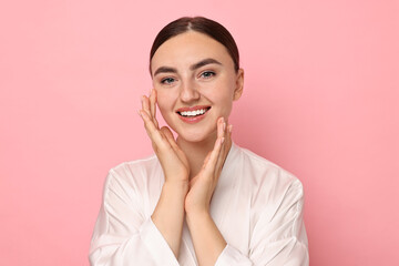 Face massage. Beautiful young woman with healthy skin on pink background