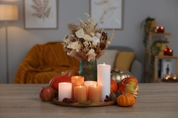 Tray with many burning candles and autumn decor on wooden table indoors