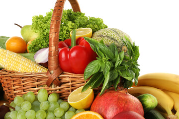 Different fresh fruits and vegetables in wicker basket isolated on white