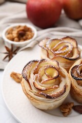 Freshly baked apple roses and walnuts on table, closeup. Puff pastry