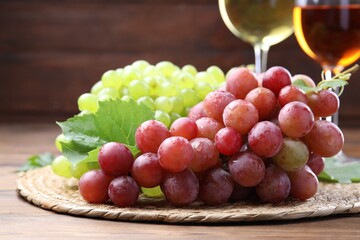 Fresh ripe grapes and glasses of wine on wooden table, closeup