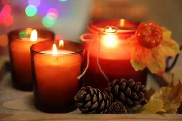 Burning candles and autumn decor on tray, closeup