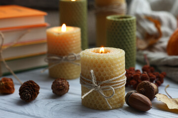 Burning candles and autumn decor on grey wooden table, closeup