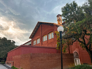 Vintage Industrial Red Brick Building with Rusted Chimney and Lamppost Under a Moody Sky in Monterrey