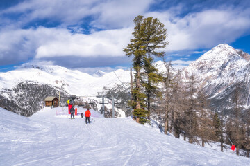 People, skiers, skiing down the slopes covered with fresh snow, Montgenevre ski village on border of France and Italy. Winter sport in Alps mountains