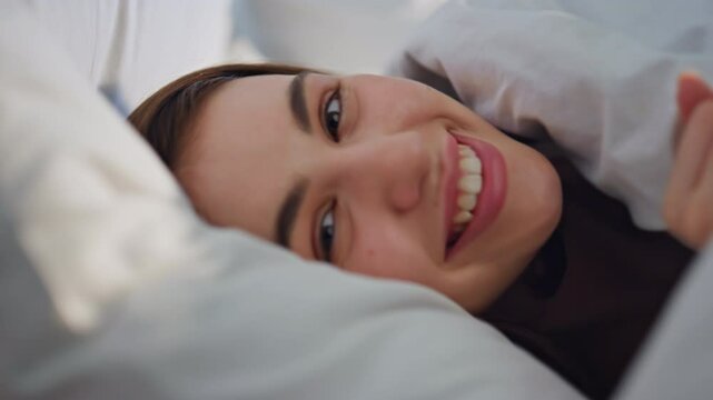 Closeup woman lying blanket in bed feeling happy closeup. Smiling lady relaxing 