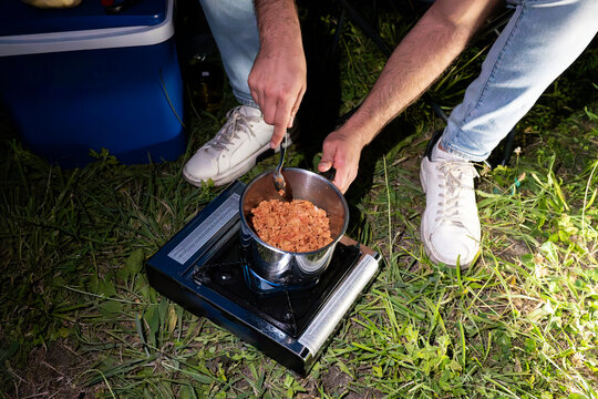Anonymous man cooking on portable stove during camping trip