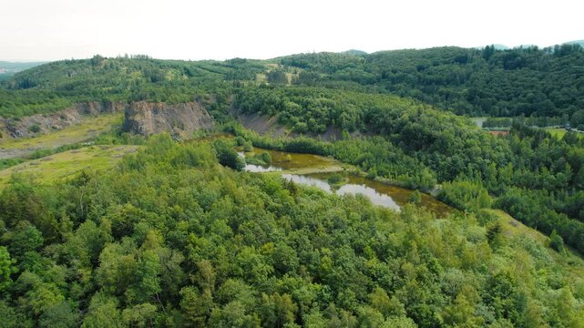 Lush forest clings to rocky outcrops in a breathtaking natural landscape, bathed in sunlight. Aerial view of river and green nature. Majestic rocky formations stand tall amidst greenery.