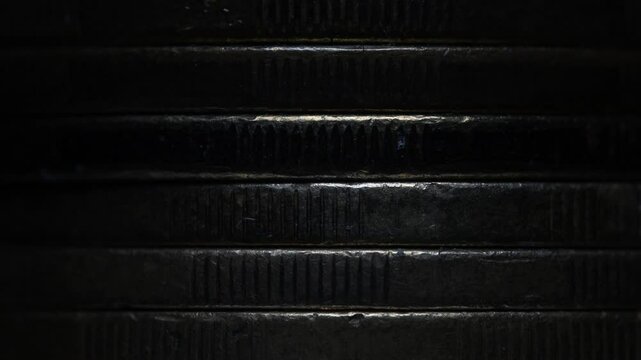 Stack of brown coins in close-up, texture of old coins, dark background, light movement, metal texture
