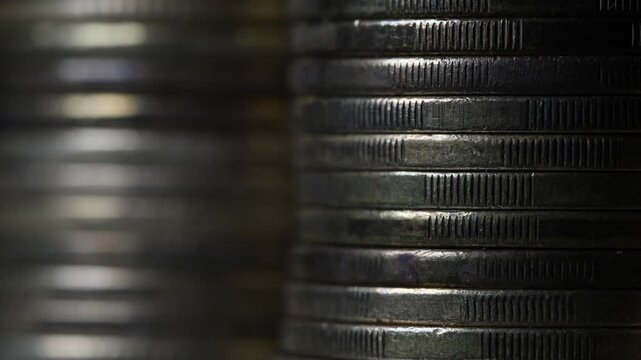 Stack of brown coins in close-up, texture of old coins, dark background, light movement, metal texture