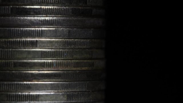 Stack of brown coins in close-up, texture of old coins, dark background, light movement, metal texture
