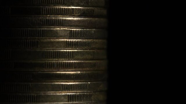 Stack of brown coins in close-up, texture of old coins, dark background, light movement 