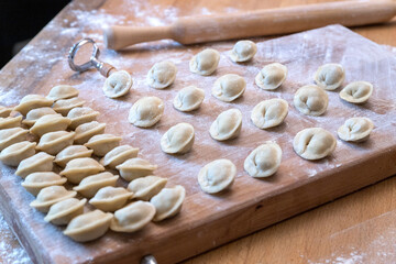 The raw dumplings were placed on a wooden cooking board. Next to it is a rolling pin for rolling...