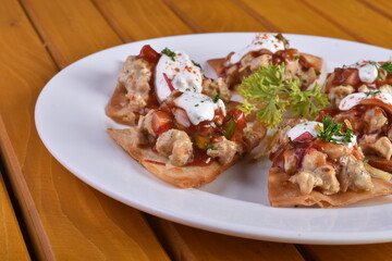 Mexican nacho chips baked with chicken, black beans and cheese on a plate top view