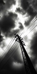 Fototapeta premium A dramatic silhouette of a power pole against a cloudy sky, capturing the essence of urban life in a moody monochrome setting.