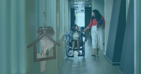 Animation of house and key over biracial businesswoman in wheelchair with colleague in office - Powered by Adobe