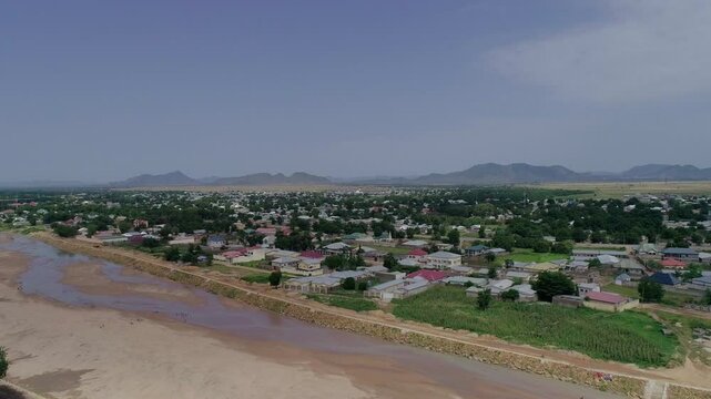 Aerial view of peaceful residential area with homes and buildings surrounded by greenery and mountains, Maroua, Cameroon.