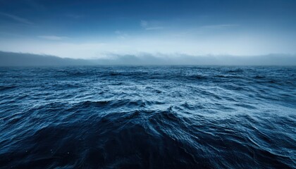 Serene Ocean Horizon at Dawn. Calm Blue Waters Meeting a Clear Sky with Gentle Dark Mist Rolling Over Distant Mountains, Creating a Peaceful and Expansive Coastal Scene in Early Morning Light