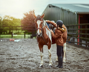 Horse, girl and adjust saddle at farm for race, sport and training at countryside ranch. Animal,...