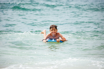 Teenage boy having a great time on blue bodyboard at the seaside