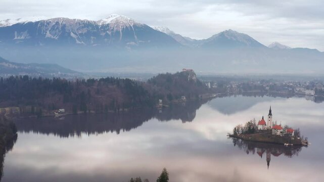 Aerial view of Assumption of Maria Church on an island surrounded by Bled Lake with scenic mountains in the background, Bled, Slovenia.