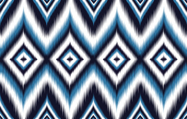 Blue and white ikat pattern. Seamless chevron design with diamond motifs. Trendy ethnic print for fashion and interiors. Abstract geometric background. Bohemian style textile. Aztec-inspired artwork.