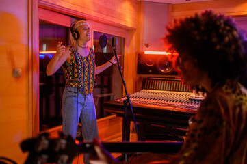 Portrait of a blonde singer woman recording a song on a microphone in a studio