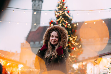 Woman at Tallinn Christmas market, framed by festive lights and the iconic Christmas tree in the background. The warm bokeh creates a magical winter atmosphere, capturing the holiday spirit in Estonia