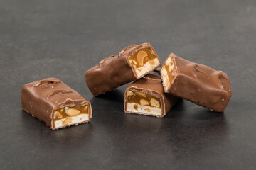 Fitness Candy bar. Nougat, caramel with peanuts, in milk chocolate. Dark gray background. Close-up