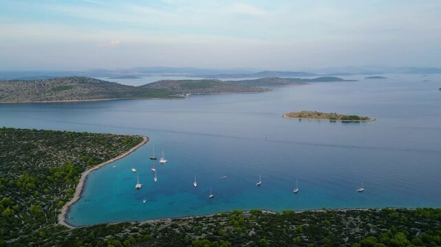 An aerial view of Vela Nozdra, a beautiful bay on the island of Kaprije, Croatia. This secluded spot, nestled between lush greenery and rocky shores, offers crystal-clear waters perfect for swimming