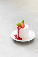 Vegan Strawberry pudding, Panna Cotta cylindrical shape. With strawberry sauce. On a plate. Close up. Light gray background