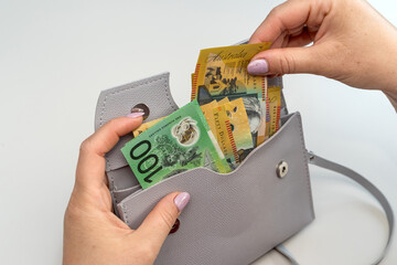 woman hold australian dollar paper bank note cash bills with grey bag. Rremoving money from wallet