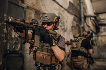 Fototapeta premium Brave soldier with sniper rifle shooting at enemy at crashed building.