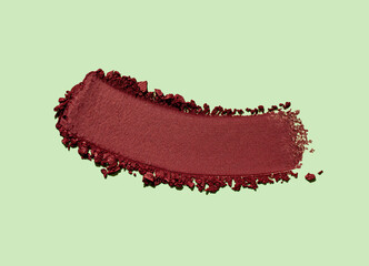 Cosmetic claret burgundy eye shadow or dry pigment texture swatch isolated on pistachio green background