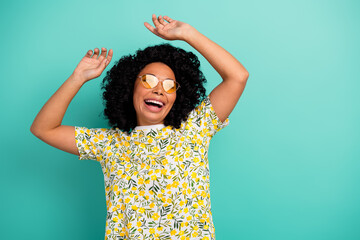 Photo of adorable lovely girl wear print t-shirt dark eyeglasses dancing empty space isolated turquoise color background