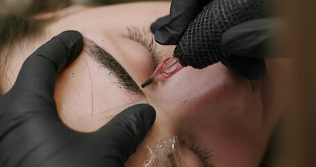 Microblading, permanent makeup tattoo close up. Master makes permanent eyebrow makeup procedure using special needle tattoo machine to woman in beauty salon. Microblading brows tattooing. - Powered by Adobe