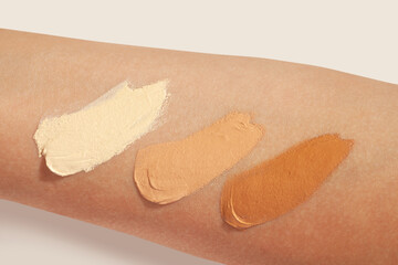 Concealer of bb cream or thick foundation light medium and dark swatches on woman hand beige...
