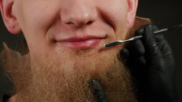 Make up artist making Disheveled blond beard for a man in theater with paint and glue, actors sfx cinema make up, close-up. Mens fashion, halloween style. making old guy.
