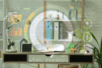 Wind turbine models with light bulb, house figures and solar panel on table in office. Green Energy concept