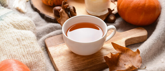 Cup of tea with aroma candle and autumn leaves on plaid