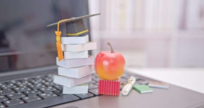 Graduate study abroad program to broaden learner's world view, e-learning concept : Graduation cap, an apple, foreign books on a laptop. Student attempting to study at a distance or learn from home.
