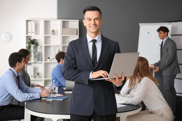 Male business consultant working with laptop in office