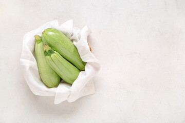 Bowl with fresh green zucchini on light background
