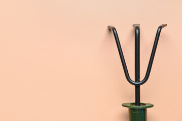 Gardening rake on beige background, closeup