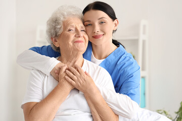 Female nurse hugging senior woman in bedroom