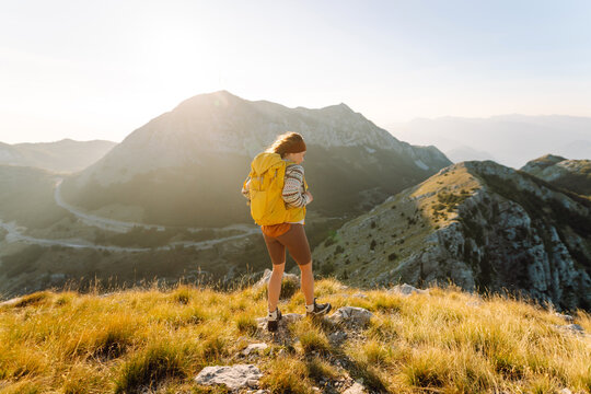 A joyful hiker enjoys the breathtaking view from a mountain summit during a sunny afternoon in the serene foothills. Nature, active life, travel.