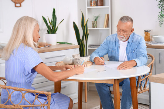 Mature couple signing divorce decree in kitchen