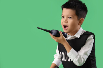 Cute little police officer with radio transmitter on green background