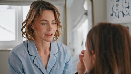 Obraz premium Positive mother talking daughter at modern bedroom closeup. Smiling lady pyjama